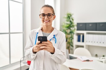 Sticker - Young blonde woman wearing doctor uniform using smartphone working at clinic