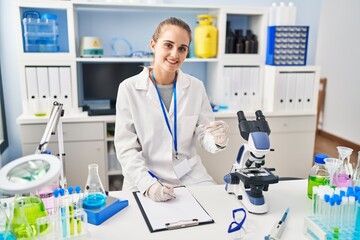 Poster - Young blonde woman wearing scientist uniform writing on checklist at laboratory