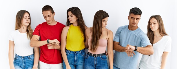 Canvas Print - Group of people wearing casual clothes standing over isolated background checking the time on wrist watch, relaxed and confident