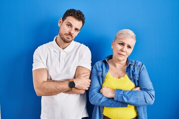 Canvas Print - Young brazilian mother and son standing over blue background looking sleepy and tired, exhausted for fatigue and hangover, lazy eyes in the morning.