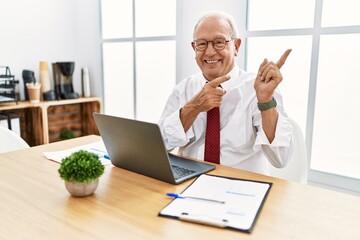 Sticker - Senior man working at the office using computer laptop smiling and looking at the camera pointing with two hands and fingers to the side.