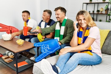 Sticker - Group of middle age friends watching and supporting soccer match talking on the smartphone at home.