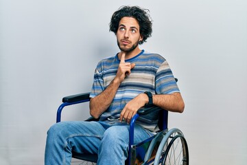 Wall Mural - Handsome hispanic man sitting on wheelchair thinking concentrated about doubt with finger on chin and looking up wondering