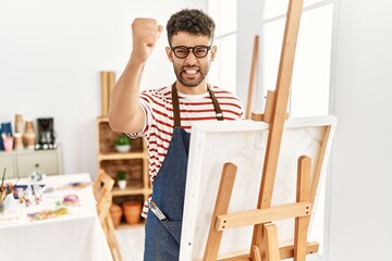 Sticker - Arab young man at art studio angry and mad raising fist frustrated and furious while shouting with anger. rage and aggressive concept.