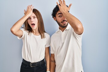 Poster - Young couple wearing casual clothes standing together surprised with hand on head for mistake, remember error. forgot, bad memory concept.