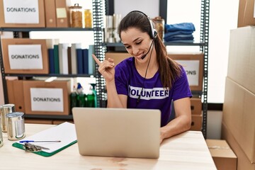 Poster - Young brunette woman wearing volunteer t shirt working at call center smiling happy pointing with hand and finger to the side