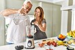 © Krakenimages.com - Middle age hispanic couple pouring water on mixer machine cooking smoothie at the kitchen.