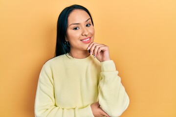 Wall Mural - Beautiful hispanic woman with nose piercing wearing casual yellow sweater smiling looking confident at the camera with crossed arms and hand on chin. thinking positive.
