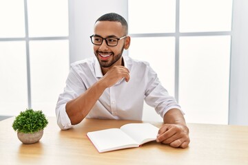 Canvas Print - Young hispanic man smiling confident reading book at office