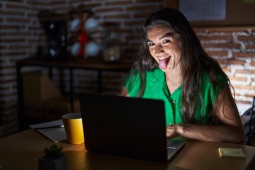 Sticker - Young teenager girl working at the office at night sticking tongue out happy with funny expression. emotion concept.