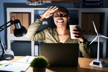 Canvas Print - African woman working using computer laptop at night very happy and smiling looking far away with hand over head. searching concept.