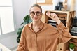© Krakenimages.com - Young blonde woman holding virtual currency bitcoin at the office looking positive and happy standing and smiling with a confident smile showing teeth