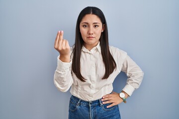 Wall Mural - Young latin woman standing over blue background doing italian gesture with hand and fingers confident expression