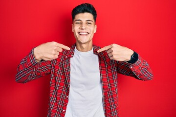 Sticker - Young hispanic man wearing casual clothes looking confident with smile on face, pointing oneself with fingers proud and happy.