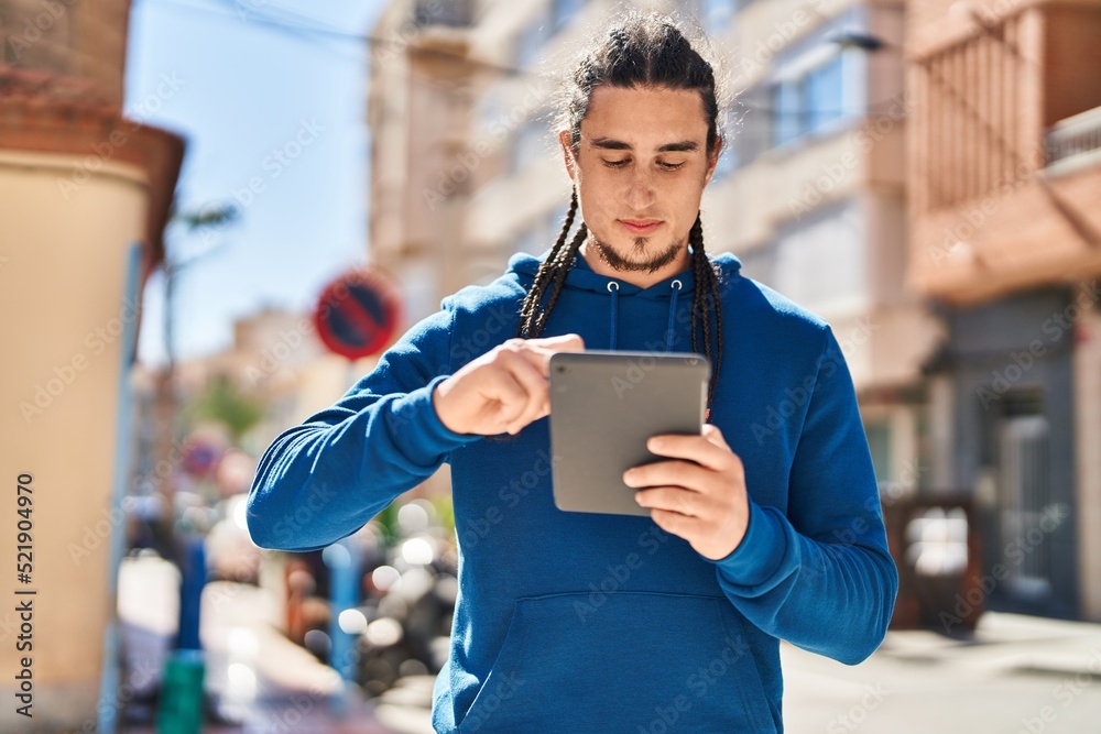 Young man using touchpad with serious expression at street