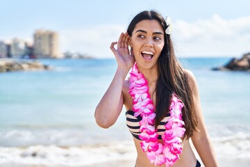 Wall Mural - Young brunette woman wearing bikini at the beach smiling with hand over ear listening and hearing to rumor or gossip. deafness concept.