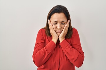 Poster - Hispanic mature woman standing over white background with sad expression covering face with hands while crying. depression concept.