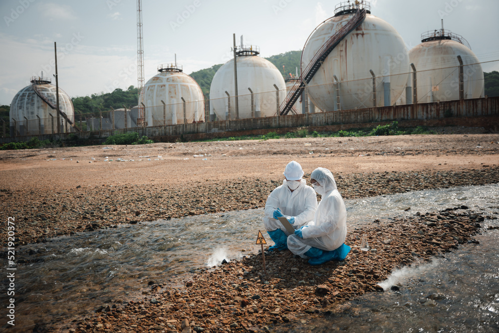 Biologist wear protective suit and mask collects sample of waste water ...