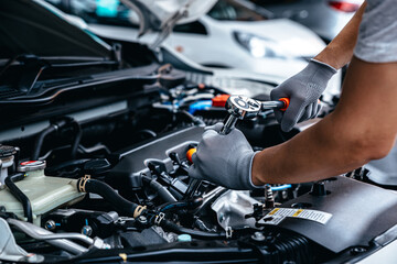 mechanic using wrench while working on car engine at garage workshop, car auto services and maintena