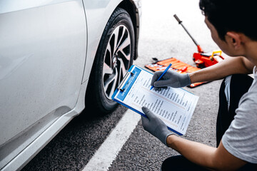 Mechanic check list to the clipboard insurance with inspecting car at garage workshop, Car auto services and maintenance check concept.