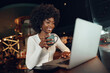 © fotofabrika - Smiling young african woman sitting with laptop in coffee shop