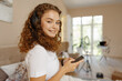 © fotofabrika - Young happy woman listening music in headphones with smartphone in bed