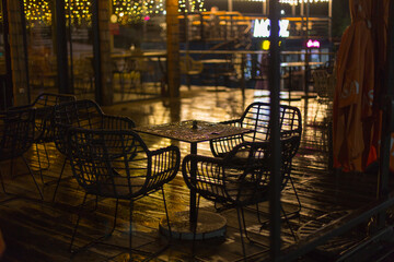 Wall Mural - chairs in a street cafe in the light of lanterns after the rain in the evening