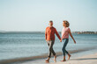 © Westend61 - Happy mature couple walking on shore at beach