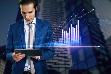 Poster - Attractive young european businessman with tablet and abstract glowing polygonal business graph hologram with growing arrow on blurry city background. Financial growth, market and trade concept.