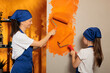 Leinwandbild Motiv Mother and child using orange paint on house walls to renovate apartment room, having fun with housework redecoration. Woman with little kid painting with paintbrush and roller.