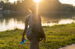 © gpointstudio - Young African American woman walking with bag and bottle of water through the park in a summer day