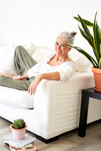 Happy Mature Woman Leaning On Armrest Of Sofa