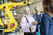 © Westend61 - Senior technician shaking hands with female colleague in factory with industrial robots