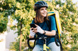 © Westend61 - Smiling delivery woman wearing helmet sitting with smart phone on bicycle