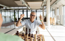 Happy Businessman Clenching Fists With Chess Piece In Office