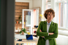 Businesswoman Wearing Green Blazer Standing With Arms Crossed In Office