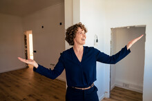Happy Real Estate Agent Standing With Arms Outstretched At New Home