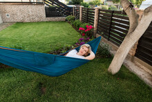 Mature Woman Relaxing On Hammock In Garden