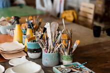 Brushes And Ceramic Plates On Workbench At Art Studio
