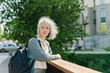 © Westend61 - Woman with backpack leaning on railing