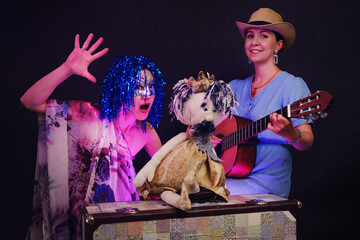 Wall Mural - Happy women in funny wigs give a musical performance on a studio black background. Smiling women showing a humorous show on a dark background