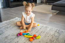 Cute Little Toddler Girl Playing At Home With Eco Wooden Toys. Happy Child Cutting Vegetables And Fruits With Toy Knife. The Child Playing Educational Games. 