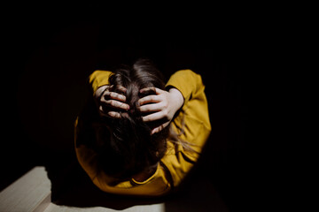 Wall Mural - Top view of unrecognisable woman suffering from depression and crying at home, holding head in her hands.