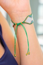 Vertical Closeup Of A Green Patterned Bead Loom Knot Bracelet On A Caucasian Female's Hand