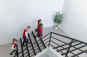 Wall Mural - High angle view of schoolchildren in uniforms walking in school staircase.