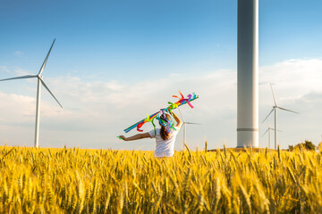 Wall Mural - Happy Little girl running in a wheat field with a kite in the summer.