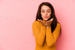 © Asier - Young caucasian woman isolated on pink background folding lips and holding palms to send air kiss.