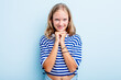 Leinwandbild Motiv Caucasian teen girl isolated on blue background keeps hands under chin, is looking happily aside.