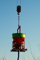 Canvas Print - A colorful concrete bucket hangs on the hook to concrete.