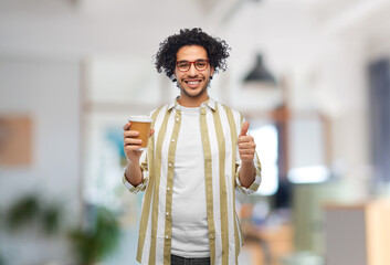 Wall Mural - drinks and people concept - smiling young man in glasses with takeaway coffee cup showing thumbs up over office background